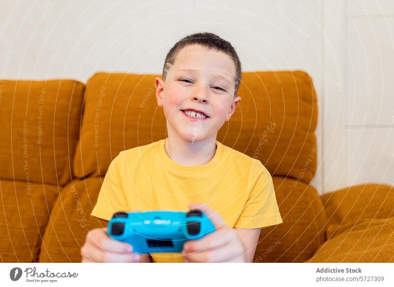 Happy child playing video games on the couch controller smile boy happy sitting leisure indoor joy blue technology entertainment gamepad fun casual gaming
