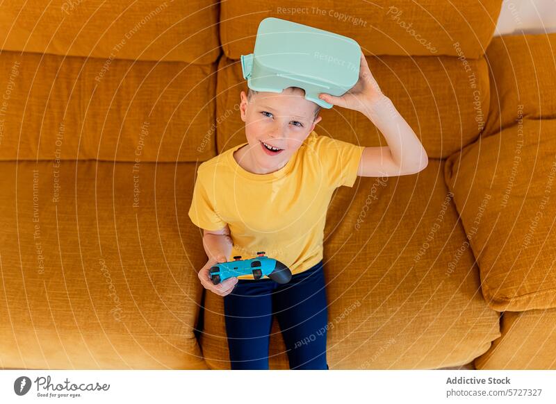 Young gamer with VR headset and controller on couch boy virtual reality vr headset gaming mustard playful expression sitting technology entertainment casual