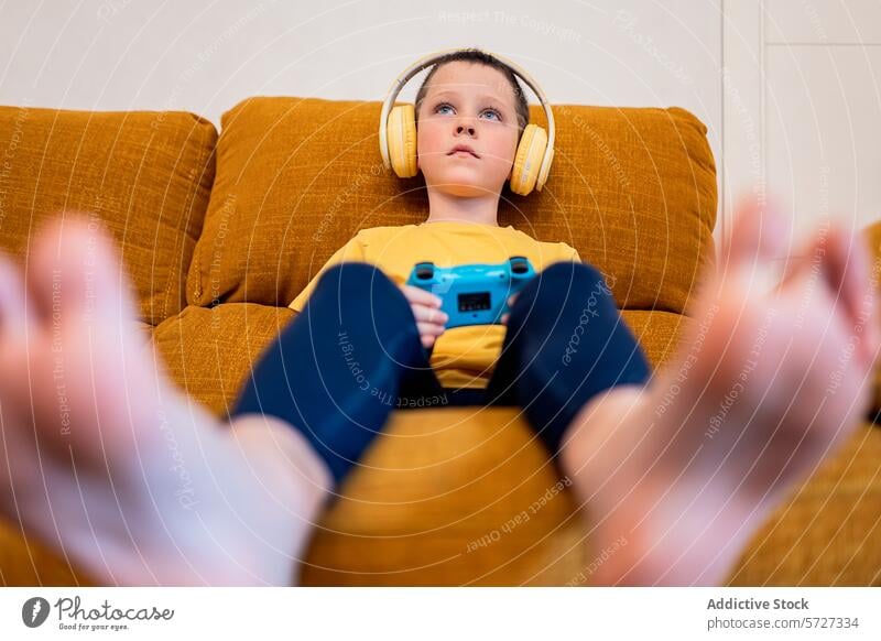 Young boy immersed in video gaming with headphones video game focused couch controller engaged young sitting brown yellow blue gamepad entertainment technology
