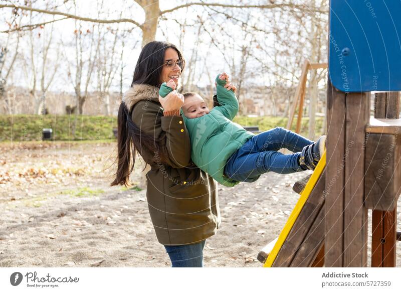 A child's laughter rings through the park as he slides into his mother's waiting arms, both sharing a moment of joy playtime woman family outdoor fun jacket