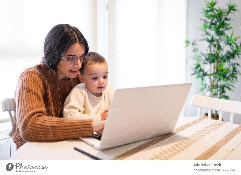 A heartwarming moment as a positive mother embraces her son while they both engage with content on a laptop at home family togetherness happiness work play joy
