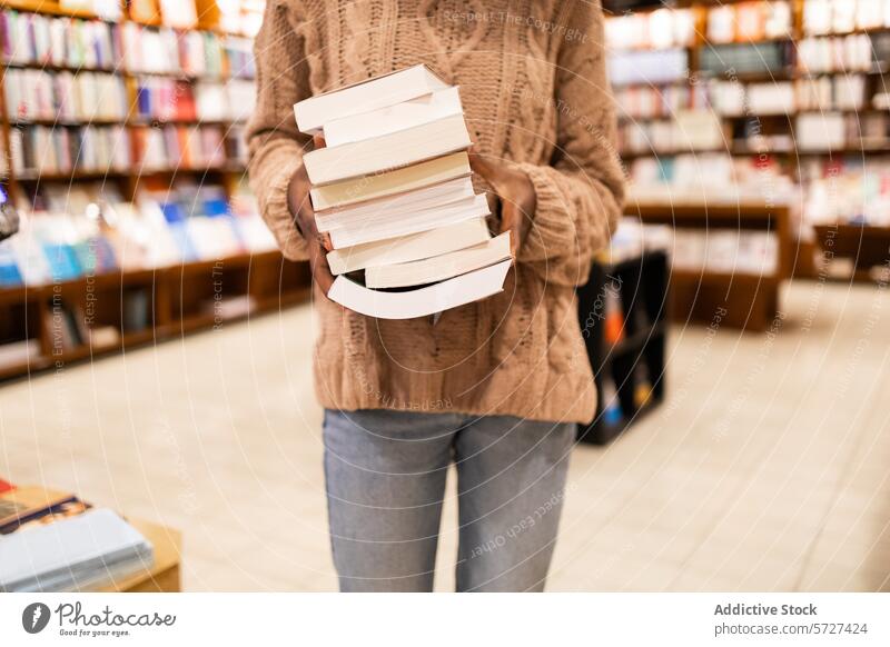 Person holding a stack of books in a library person literature reading education knowledge learning bookshelf aisle collection sweater close-up study academic