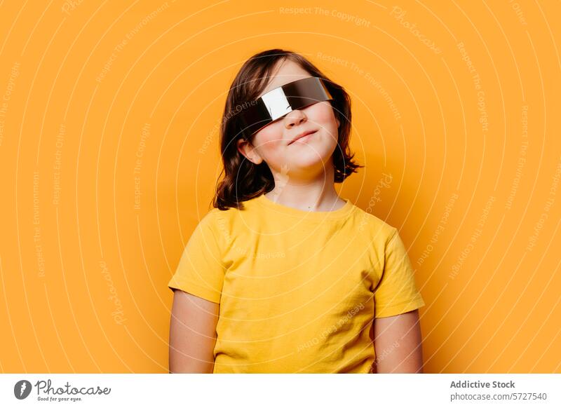 Smiling child with futuristic sunglasses on orange background smile girl beaming oversized vivid backdrop children happy joy youthful fashion trendy accessory