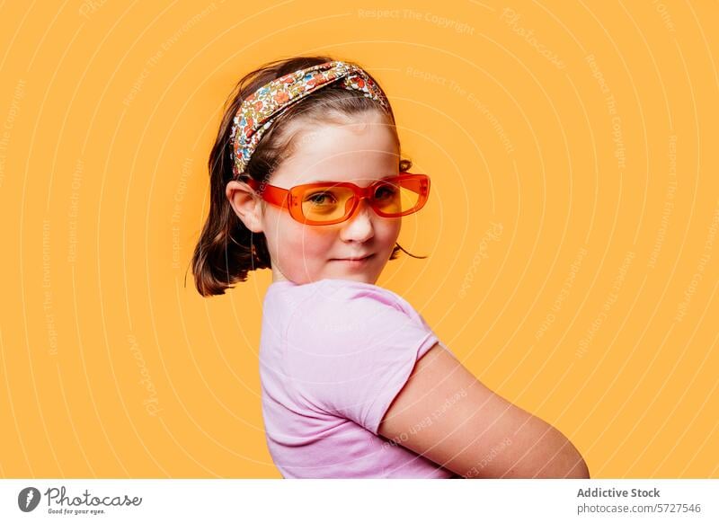 Young girl with stylish sunglasses over orange background young child kid cute headband confidence pose backdrop playful cheerful fashion childhood happy trendy