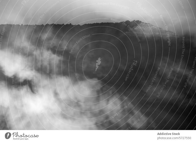 Misty mountain peak emerging from clouds mist black and white landscape nature fog mysterious ethereal outdoors monochrome obscured tranquility atmospheric