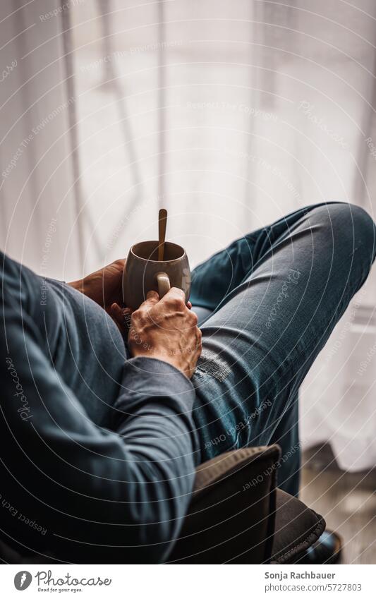 A man sits with a coffee cup in front of a patio door Man Sit Chair Patio door Coffee cup 50-60 Jeans Blue hygge Break more adult color photograph person