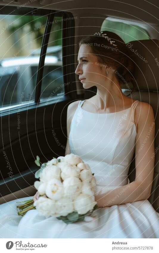 bride with a black car near a glass skyscraper hotel road white grey asphalt blue building wedding bouquet stand inside going out hairstyle