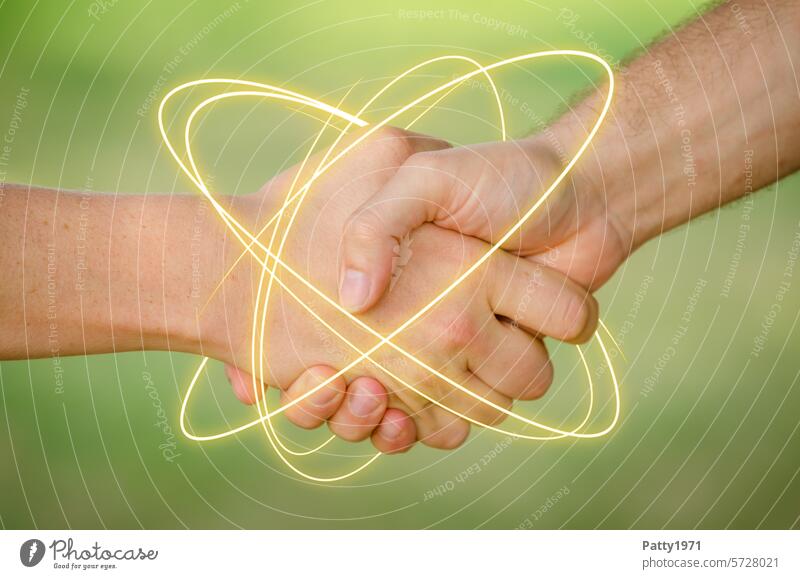 Two young men shake hands. A neon light trail circles the hands, close-up of the hands against a green background. handshake Handshake Teamwork Energy