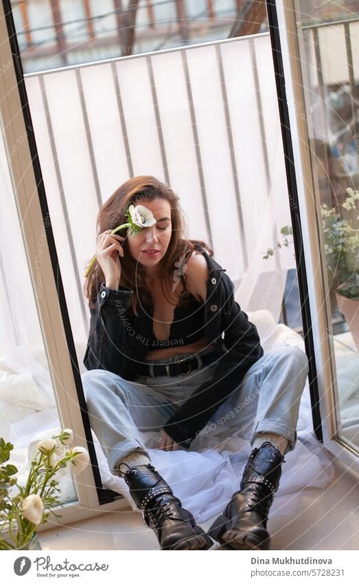 beautiful woman in grunge outfit with white flower sitting on the balcony of apartment 25 to 30 years Young woman Grunge grunge look Clothing outfits female