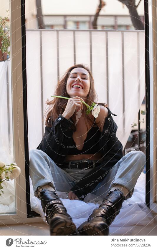 beautiful woman smiling in grunge outfit with white flower sitting on the balcony of apartment 25 to 30 years Young woman Grunge grunge look Clothing outfits