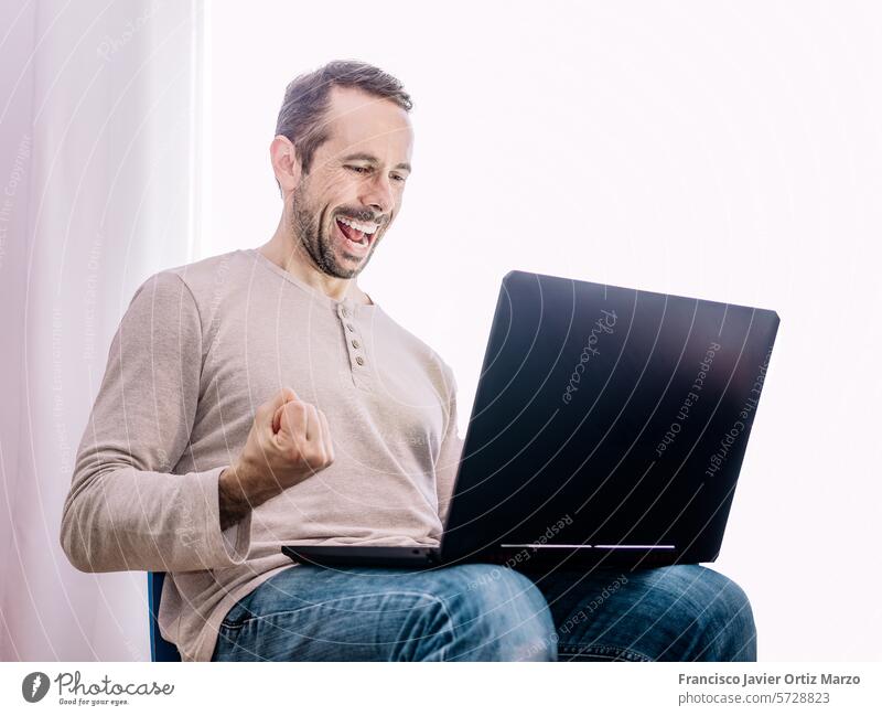 Man looking at his laptop, happy to success in his work man excited one caucasian person shirt celebration blue adult computer working internet occupation
