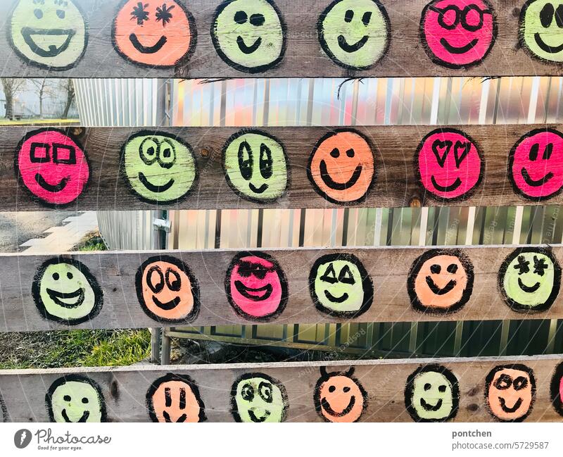 lots of colorful smiling smileys on a temporary picket fence in front of a construction site Smileys neon Laughter Good mood variegated street art