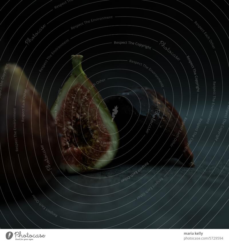 The image features a few figs placed on a black surface. purple fruit fruits seed red green pear shape