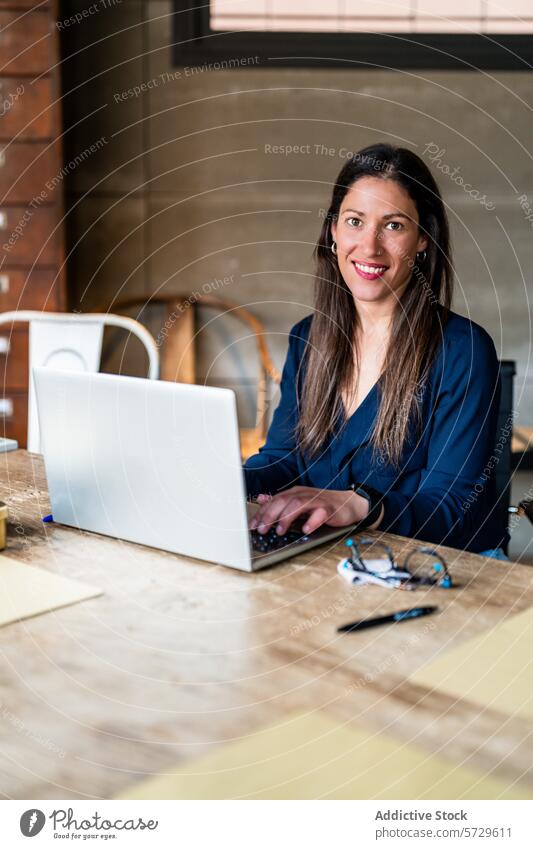 Female Entrepreneur Working on Laptop at Desk woman entrepreneur laptop desk working smiling looking at camera business office confident professional friendly
