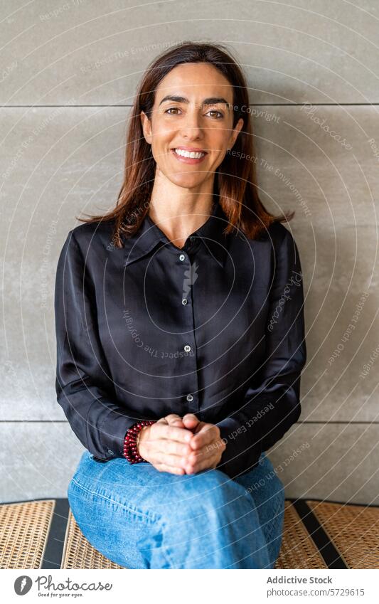 Confident businesswoman smiling in casual office attire looking at camera entrepreneur female professional confident black shirt jeans long hair seated modern