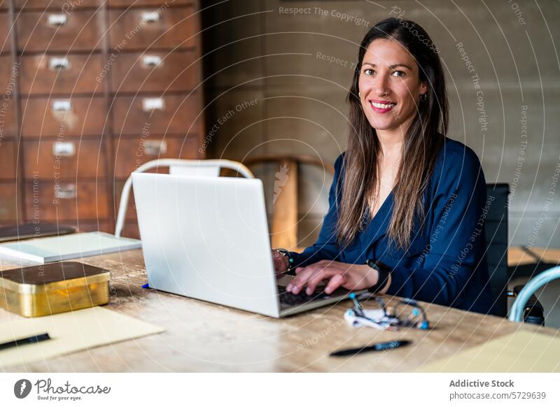 Professional woman working at her laptop in office professional entrepreneur confident looking at camera female business modern startup women-led company