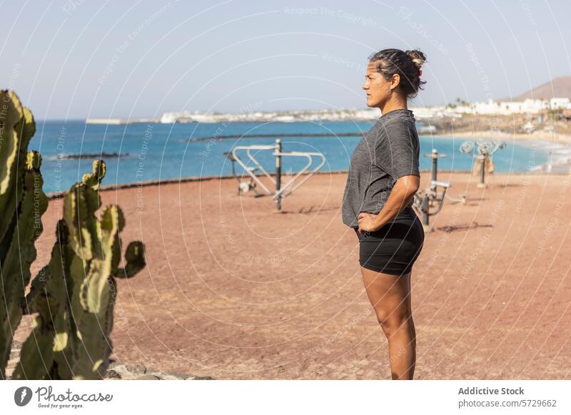 Contemplative woman facing away at a beach side gym outdoor fitness sea contemplative looking away workout leisure active lifestyle coast nature back view
