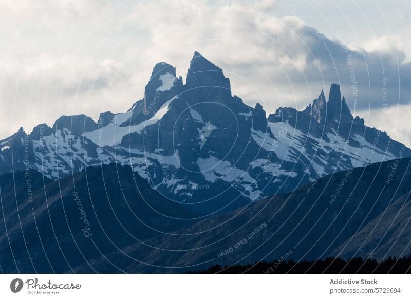 A stunning display of Patagonia's rugged mountain landscape under the soft light of evening, showcasing the dramatic silhouettes and snow patches peak dusk
