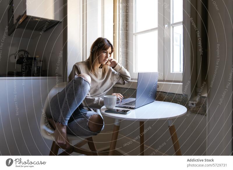 Thoughtful woman working from home near window laptop coffee table thoughtful sitting young technology internet remote job casual sweater jeans torn cozy modern
