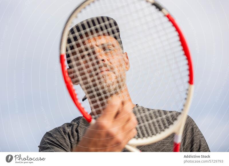 Tennis player with racket obscuring his face tennis man obscured sports equipment holding grip strings athlete active court game playing outdoor leisure
