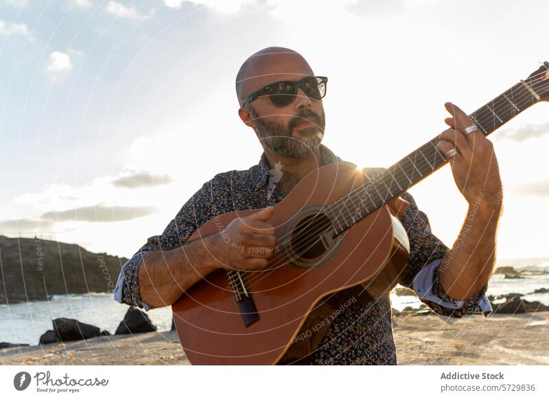 Man playing guitar by the sea at sunset man male acoustic musician beach instrument waves crashing background atmosphere outdoor leisure hobby performance art