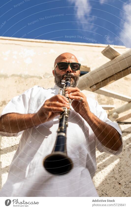 Bearded man playing clarinet outdoors on sunny day male musician beard sunglasses blue sky performance jazz international day culture art instrument