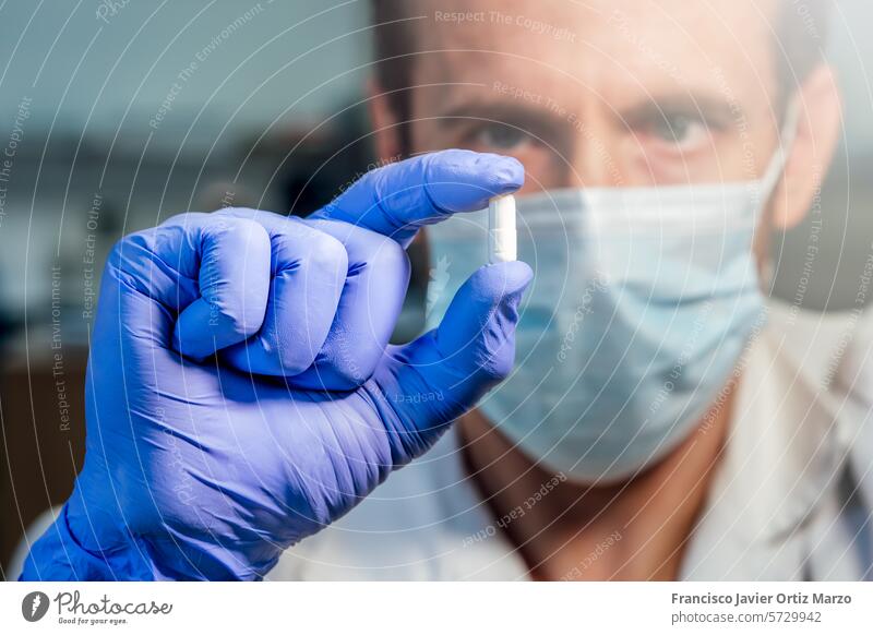 Scientist with medical mask showing white pill. Research concept. Selective focus. laboratory medicine scientist research doctor pharmacy science person health