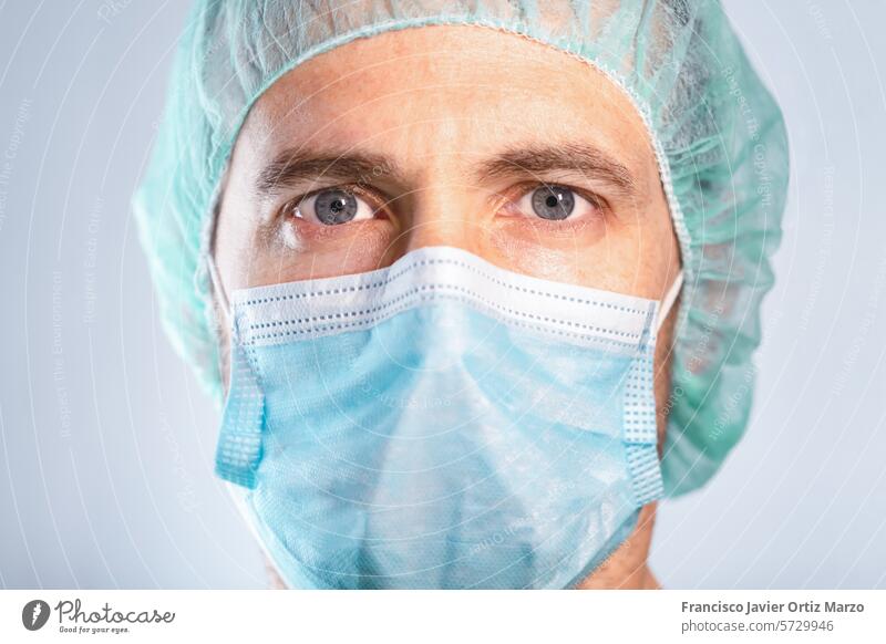 Close-up of doctor with blue eyes protected by mask and cap. Selective focus. medicine scientist man face mask biotechnology care scientific caucasian
