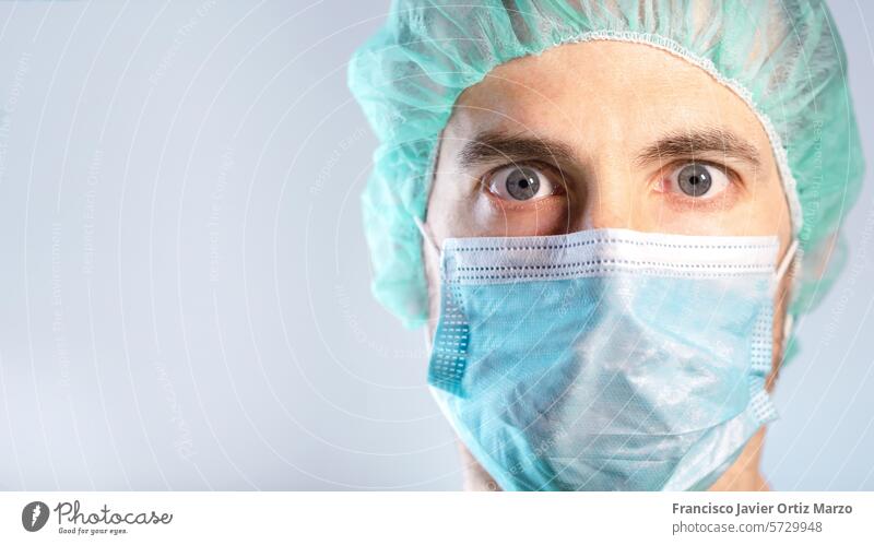 Close up of surprised and worried doctor's face protected by a mask. Selective focus man face mask portrait adult scientific medicine isolated shocked illness