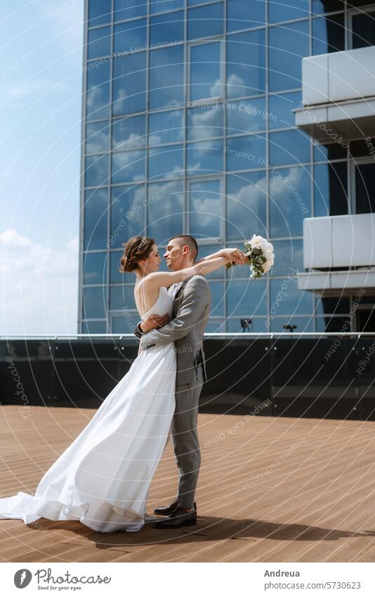bride and groom first meeting on the roof of skyscraper blue bouquet city couple day dress forever happiness joy newlyweds smiles suit summer together top two