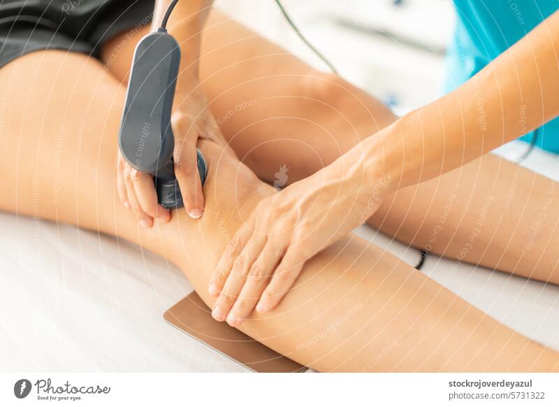 A physical therapist applies radiofrequency waves with a diathermy machine to relieve her patient's knee muscle pain physiotherapist clinic rehabilitation heat