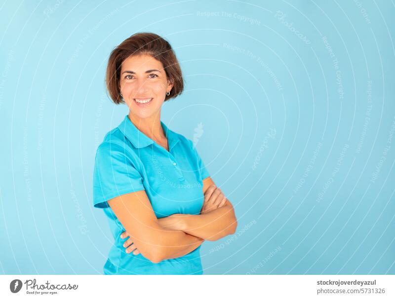 A woman, a physiotherapist, poses with a confident gesture, looking at the camera on a blue background, wearing a blue T-shirt portrait person female t-shirt