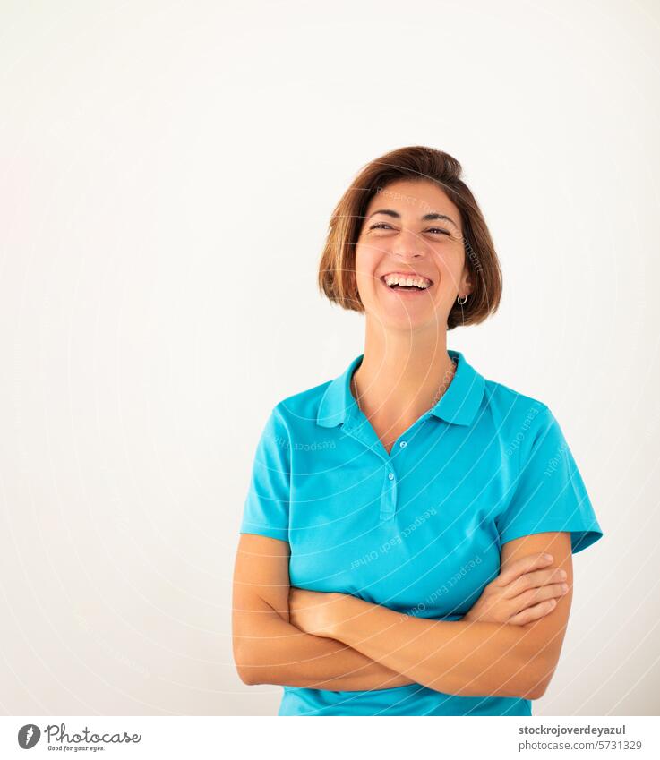 A woman, owner of her own physiotherapy clinic, smiles confidently, on a plain white background physiotherapist women female adult laugh arms crossed caucasian