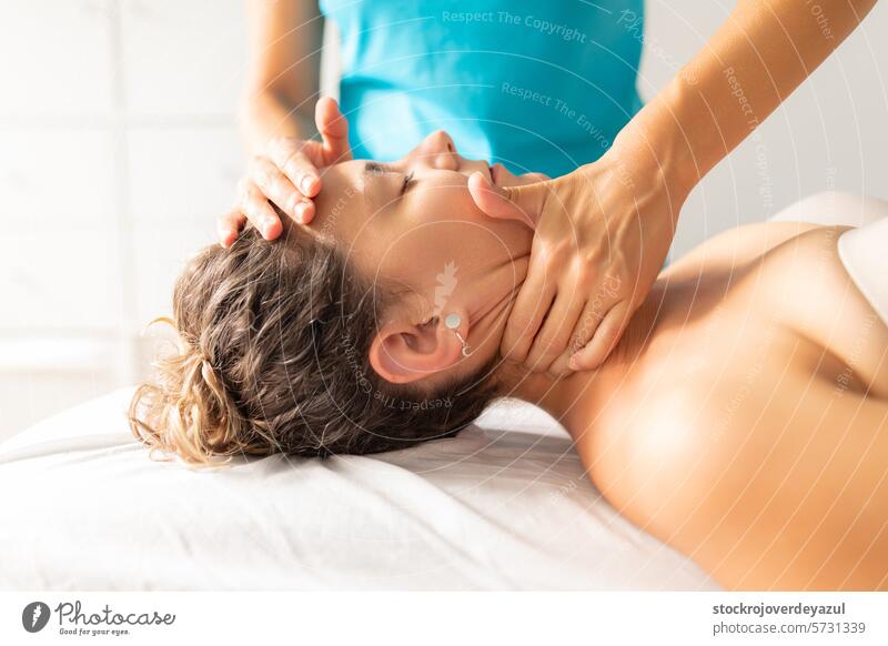 A physiotherapist performs a decontracting and relaxing massage on her patient's neck to relieve her of pain and tension clinic rehabilitation health care