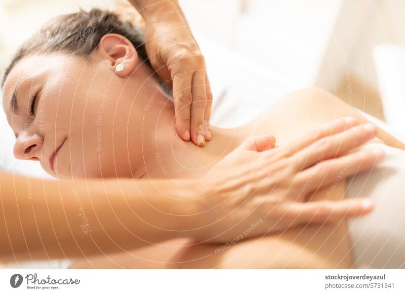 A patient, completely relaxed, enjoys receiving a massage from her physiotherapist in the neck area clinic rehabilitation physiotherapy health care treatment