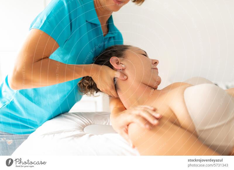 A female physiotherapist performs a stretching exercise on her patient's neck and shoulder clinic rehabilitation physiotherapy care massage stretcher