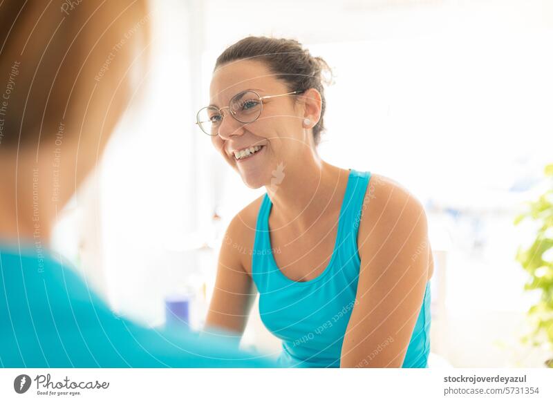 A woman patient talks cheerful to her physiotherapist after receiving a manual therapy session clinic rehabilitation physiotherapy women female talking person