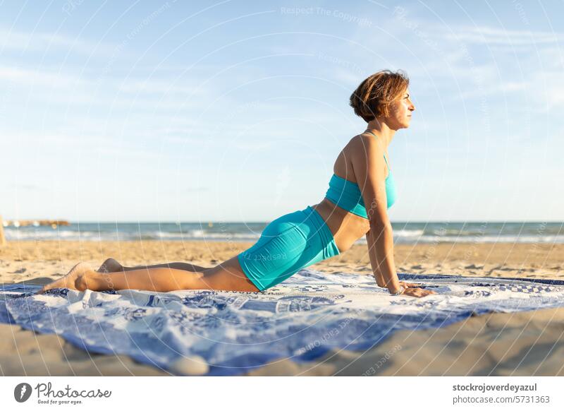 A woman practices Pilates on the beach, and performs the swan movement exercise pilates yoga mediterranean spain mind-body exercise contrology sunset