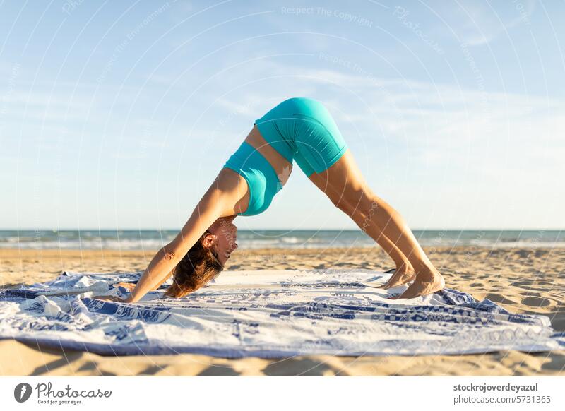 A middle-aged woman performs Pilates exercises on the beach to stay fit pilates yoga mediterranean spain mind-body exercise contrology sunset sport fitness pose