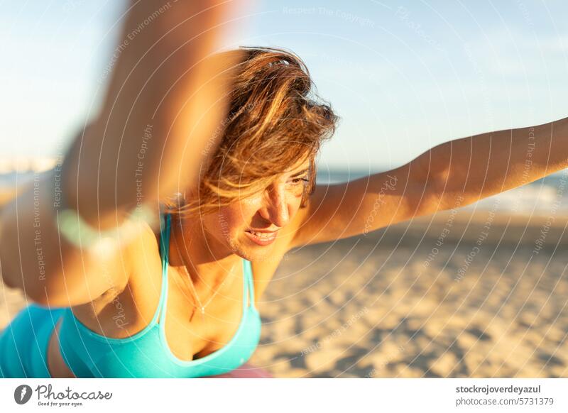 A woman performs exercises and pilates movements on the beach to stay fit yoga mediterranean spain mind-body exercise contrology sunset fitness sport healthy