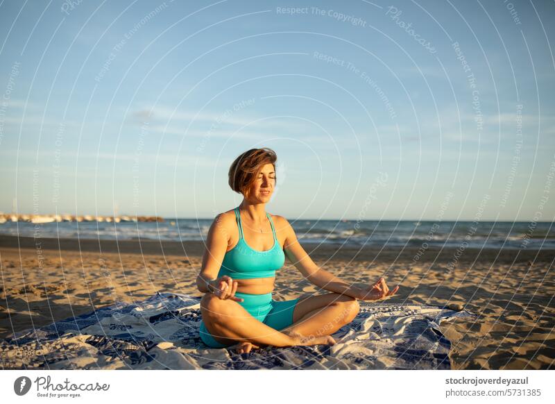 A woman performs meditation exercises on the beach, after a Pilates session at sunset yoga mediterranean spain meditating sea female nature summer relaxation