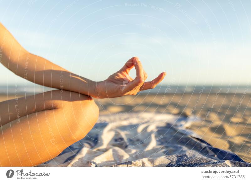 Woman's hand while she performs meditation exercises on the beach, after a Pilates session at sunset yoga mediterranean spain mind-body exercise woman lifestyle