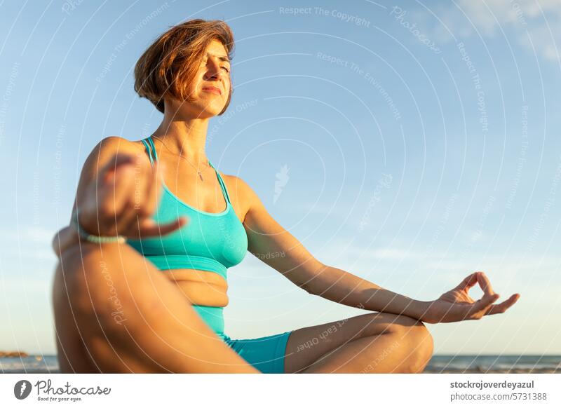 A woman performs meditation exercises on the beach, after a Pilates session at sunset yoga mediterranean spain fitness healthy real people lifestyle mind
