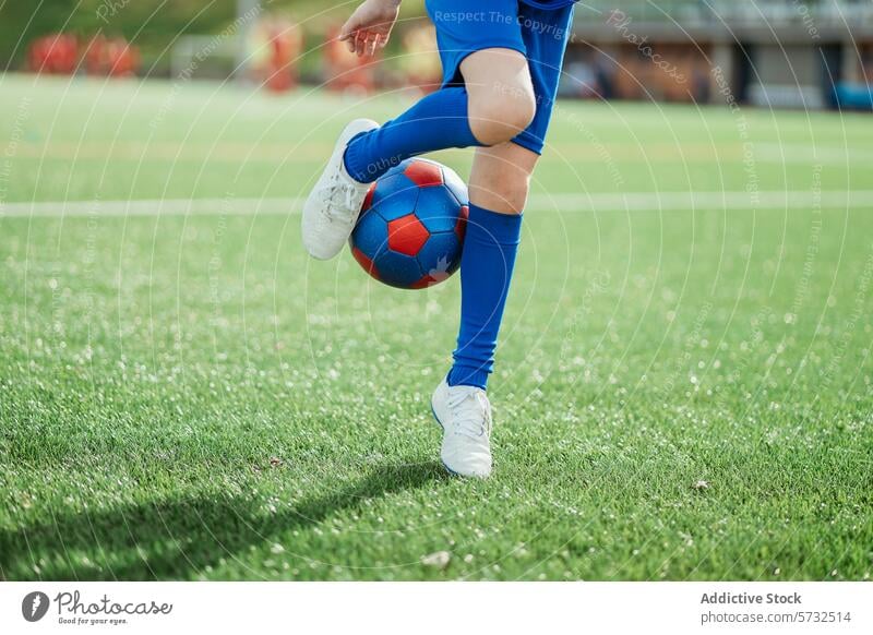 Close-up of a soccer player controlling the ball on field ball control foot pitch green lush sport athletic practice skill blue attire grass football cleat