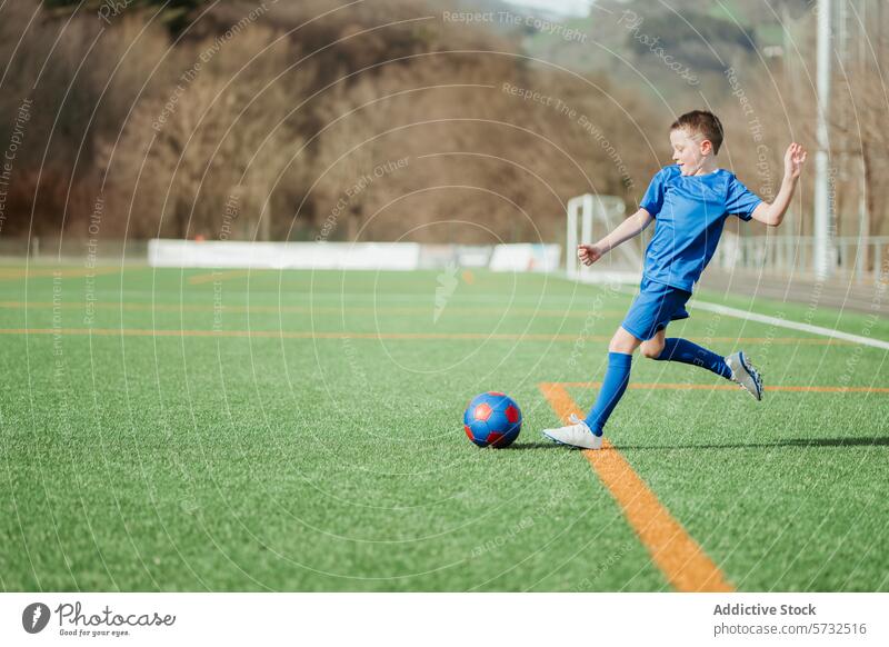 Youth soccer player in action on a sunny day youth young boy blue uniform active running ball green field sport game outdoor physical activity healthy lifestyle