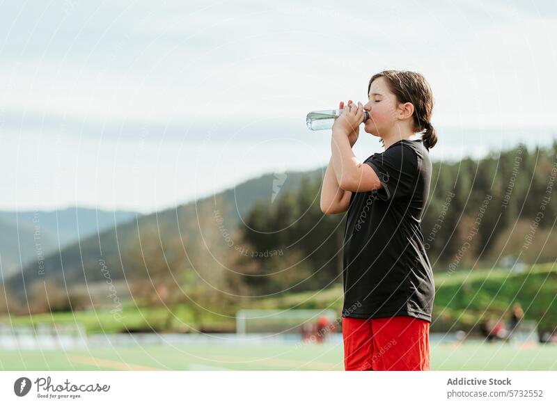 Young athlete drinking water on sunny field girl hydration water bottle sport break young active health fitness exercise training outdoor leisure refreshment