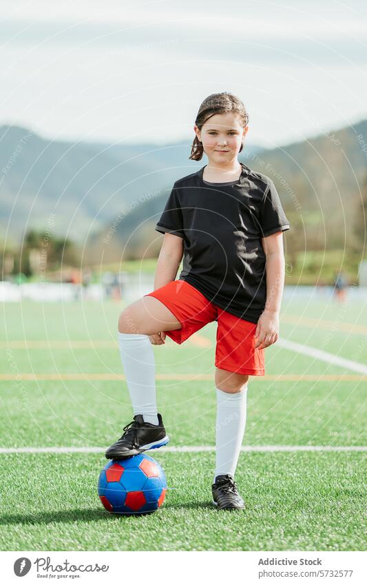 Young girl posing with soccer ball on field sport nature confidence pose foot rest colorful attire outdoor young athlete sporty casual leisure exercise activity