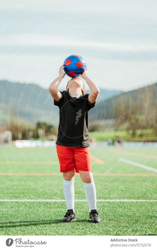 Young athlete practicing throwing technique with ball soccer field young practice sport overhead ready lush grass outdoor daytime male person physical activity