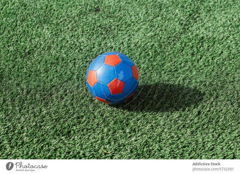 Colorful soccer ball on lush green artificial turf grass sport play outdoor equipment game field synthetic leisure recreational colorful blue red texture ground
