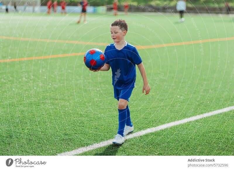 Young boy enjoying soccer practice in blue uniform child ball sport playing field turf artificial green walk hold football kid sportswear cleats activity